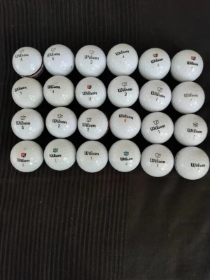 Wilson vita golfbollar, 24-pack - Säljer 24 stycken vita golfbollar från Wilson. Bollarna har olika nummer och logga tryckt i svart, rött eller blått. Perfekt för dig som vill fylla på golfbagen inför säsongen. Klassisk rund form och tillverkade i slitstarkt material.
