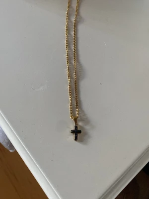 Guldkors halsband - Guldsmycke med ett kors i svart.
