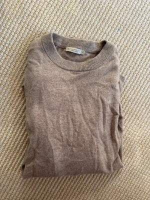 Beige cashmeretröja från Suitsupply - Säljer en beige stickad tröja från Suitsupply i 100% cashmere. Tröjan har rund halsringning och ribbade muddar vid halsen. Perfekt för dig som gillar stilrena och mjuka plagg i neutrala färger.