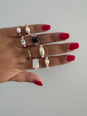 Flera ringar med pärlor och stenar - Säljer ett set med unika ringar i olika former och färger. Perfekt för dig som gillar att mixa och matcha accessoarer. Storlek 17-18 