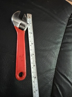 Justerbar skiftnyckel med rött handtag - En klassisk justerbar skiftnyckel med rött plastöverdraget handtag och metallhuvud. Perfekt för att lossa eller dra åt muttrar och bultar. Längden är cirka 15 cm. Praktiskt verktyg för hemmaprojekt eller cykelmeck.