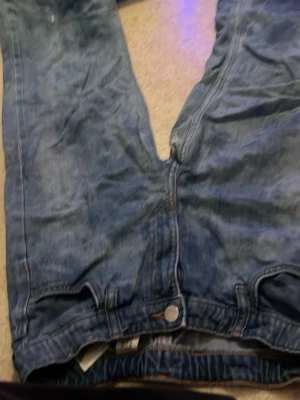 Blåa baggy jeans med raka ben strl 146 - Bytar ett par blåa jeans med baggy passform och raka ben. Jeansen har klassisk femficksdesign och knappgylf. Materialet är denim i bomull och färgen är tvättad blå med slitningar för en avslappnad look.