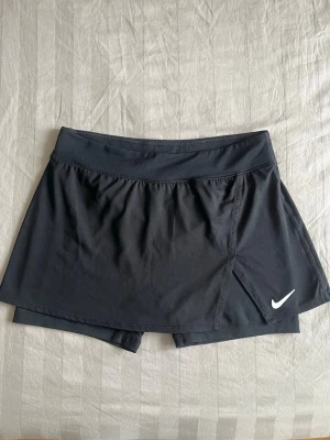 Tenniskjol Nike - Tenniskjol med inbyggda shorts. Passar S-M