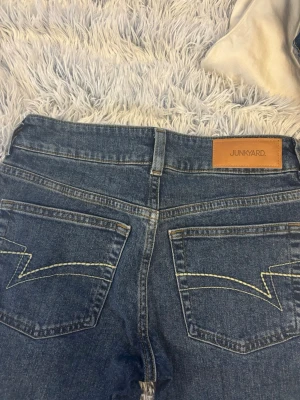 Blå raka jeans från Junkyard - Snygga blå jeans från Junkyard med raka ben och klassisk femficksmodell. Jeansen har kontrastsömmar och coola detaljer på bakfickorna. Tillverkade i slitstarkt denimtyg med en tidlös tvätt som passar till det mesta.