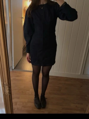 Mörkblå jeansklänning med knappar - Snygg mörkblå jeansklänning med långa ärmar och knappar hela vägen framtill. Klänningen har en figurnära passform och markerade sömmar som ger en cool look. Perfekt att styla med strumpbyxor och boots. Från Kappahl i storlek xs och aldrig använd💓