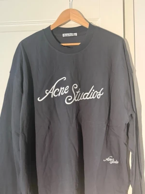 Svart sweatshirt från Acne Studios - Vvart sweatshirt från Acne Studios med vit broderad logga framtill. Tröjan har rund halsringning och långa ärmar. Perfekt för en avslappnad och trendig look. Materialet känns mjukt och bekvämt mot huden.