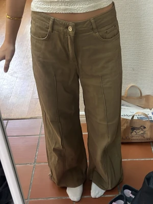Vida militär gröna jeans med medelhög midja -  Säljer ett par gröna  jeans med vida ben och hög midja. Jag är 173 lång och de  Jeansen har klassiska fickor, bälteshällor och knappgylf. Materialet känns mjukt och bekvämt, perfekt för en avslappnad stil. Passar dig som gillar loose fit och trendiga siluetter. Baggy widd