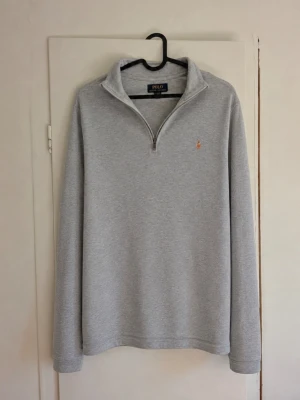 Polo Ralph Lauren Half-Zip Grå – XL (18–20) 🐎 - Klassisk ljusgrå half-zip från Polo Ralph Lauren med broderad multicolor Pony-logga på bröstet. Stilren och lättmatchad modell med hög krage och quarter zip. Storlek: XL (18–20) ungdom Färg: Ljusgrå Skick: Begagnat skick. Ett mindre hål/defekt finns i tyget, se närbild. I övrigt fint skick. Detaljer: Half-zip/quarter zip och broderad Polo-logga. QR-/produktetikett finns kvar, se bilder. Hör gärna av dig vid frågor eller om du vill ha mått! 📏