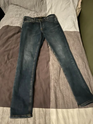 Jack and Jones mörkblå slim jeans med stretch  - Snygga mörkblå slim jeans med lätt slitning och klassiska fem fickor. Jeansen har smal passform och är tillverkade i ett stretchigt denimtyg för extra komfort. Perfekta till en avslappnad look och passar till det mesta i garderoben.
