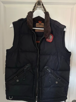 Svart parajumpers med pälskrage - Snygg svart dunväst från Parajumpers med päls på kragen, sällsynt väst då den inte säljs längre! Fint skick. Storlek M