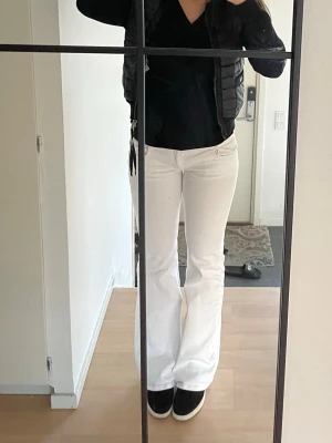 Vita bootcut jeans med fickdetaljer subdued - Säljer ett par vita bootcut jeans med snygga fickor bak med lock och knappdetaljer. Jeansen har normal midja och klassisk femficksdesign. Perfekta för dig som vill ha en clean och fräsch look till vardags. Subdued Ksk liiiiteeee mörkare Wash längst ner vid hälen, blir naturligt så med vita jeans