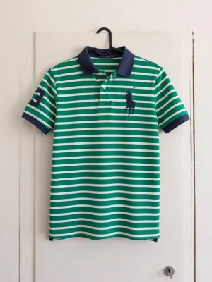 Polo Ralph Lauren randig piké – grön/vit Big Pony - Snygg klassisk piké från Polo Ralph Lauren 💚🤍 Grön- och vitrandig med marinblå krage och ärmslut. Stor broderad Big Pony-logga på bröstet samt nummer 3 på ärmen. Perfekt till sommaren och riktigt snygg till jeans eller shorts. Preppy/vintage känsla och lätt att styla. Storlek: M (10-12) Skick: Bra! Inga tydliga fläckar eller skador förutom att den är lite missfärgad! Kan skicka fler bilder eller mått vid intresse! 📦