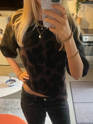 Mörkbrun leopardmönstrad stickad tröja - Säljer en trendig stickad tröja i mörkbrunt med svart leopardmönster och halvkort ärm, slutsåld online perfekt nu inför hösten💕😊