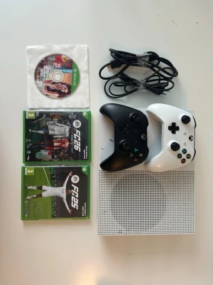 Xbox One S med två handkontroller - Säljer en vit Xbox One S med två trådlösa handkontroller (en svart och en vit), strömkabel samt tre spel: GTA V, EA Sports FC 24 och EA Sports FC 25. Priset kan diskuteras vid snabb affär!!!