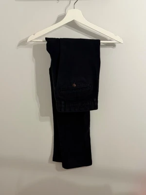Snygga kostymbyxor!  - Snygga svarta chinos med klassisk passform och bakficka med knapp. Byxorna har raka ben och är tillverkade i ett mjukt bomullstyg som ger en skön känsla. Perfekta för dig som vill ha en stilren och enkel look.