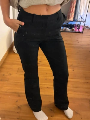 Svarta raka kostymbyxor - Snygga svarta kostymbyxor med rak passform och hög midja. Byxorna har hällor för skärp och diskreta sidofickor. Perfekta för en clean och stilren look. 