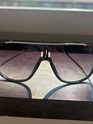Svarta pilotbågar solglasögon - Snygga solglasögon med svarta pilotbågar och stora, tonade glas. Klassisk och trendig design som passar till många olika stilar. Bågarna har en metallkänsla och glasen är lätt rökfärgade för en cool look.