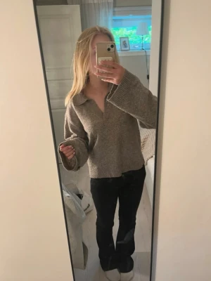 Beige stickad tröja med krage - Mysig beige stickad tröja med krage och v-ringad hals. Tröjan har långa ärmar och ribbade muddar vid ärmslut och nederkant. Perfekt för lager på lager och chill stil.