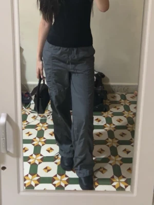 Grå cargobyxor med raka ben - Snygga grå cargobyxor med raka ben och flera fickor på sidorna. Byxorna har en avslappnad passform och är tillverkade i ett lätt tyg som ger en cool streetwear-vibe. Perfekta för dig som gillar en casual och trendig stil.