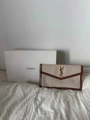 YSL clutch - YSL clutch köpt på Vestaire Collective med en liten defekt som tillkommit under ägandeskap skriv för fler bilder, pris är diskutabelt. !!! MAN FÅR DUSTBAG OCH LÅDAN I KÖPET !!!!!!