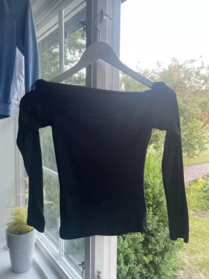 Svart offshoulder topp - Säljer en svart offshoulder topp med lång ärm. Toppen har en tight passform och är tillverkad i ett stretchigt material som sitter snyggt på kroppen. Perfekt för dig som gillar en stilren och enkel look.Y2k off shoulder svart lång tröja i storlek xxs ifrån hm