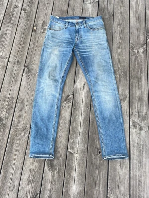 Ljusblå slim fit jeans - Snygga ljusblå jeans i slim fit-modell med klassisk femficksdesign och slitningar framtill. Jeansen har normal midja och raka ben, tillverkade i denim med en tvättad look för en avslappnad stil. Riktigt feta fades på dessa! Storlek W28- L 32.