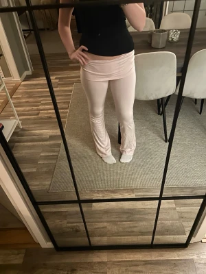 Ljusrosa utsvängda leggings - Säljer ett par ljusrosa leggings med utsvängda ben och hög midja. De är stretchiga och sitter tajt upptill men släpper ut vid anklarna. Perfekta för en avslappnad och trendig look.