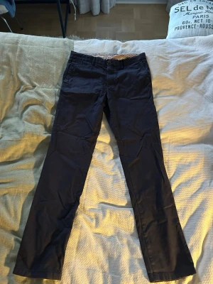 Tommy Hilfiger Bleeker Chinos – Blå – Strl M - Snygga blå chinos från Tommy Hilfiger, modellen Bleeker Stretch Slim Fit, i storlek M. Använda väldigt lite och i toppskick – hela och fräscha utan tydligt slitage.  Nypris: ca 999 kr Pris: 539 kr – öppen för bud!  Skickas snabbt och packas omsorgsfullt.