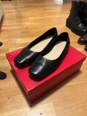 Svarta ballerinaskor i skinn WERA - Stilrena svarta ballerinaskor med fyrkantig tå och låg klack. Skorna är tillverkade i slätt skinn och har en enkel, klassisk design som passar till många olika outfits. Insidan är ljus och sulan är tunn för en smidig känsla. Använt ett fåtal gånger, vid frågor eller om ni vill ha fler bilder är det bara att höra av sig! (Små märken på skorna vid fronten)