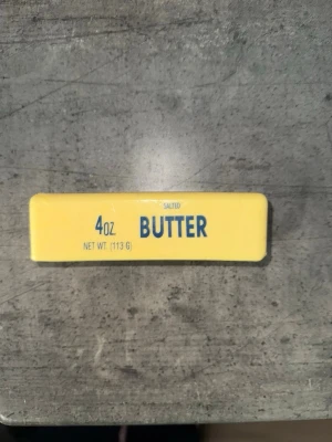 Squishy - En klassisk gul smörstav på 113 gram (4 oz) med texten 'BUTTER' i blått. Perfekt till bakning eller matlagning. Rektangulär form och tydlig viktangivelse på förpackningen.