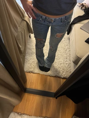 True religion low Rise Nelly - Blå true religion X Nelly jeans med rosa sömmar i storlek W24. De har används flera gånger och längst ner har de skrapat i marken, men i övrigt är dem i bra skick. De är självuppsydda av mig så innerbenslängden är 73 cm (jag är 155 cm). Jag har också själv gjort hålen💗💗 