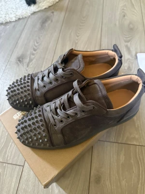 Grå Christian Louboutin skor - Gråa Christian Louboutin skor med mocka, använda cirka 3 gånger men är som nya, det finns dustbag,äkthetsbevis, kvitton. Storlek 42