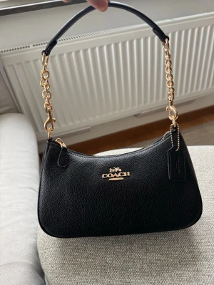 Svart axelremsväska från Coach - Svart väska av faux leather i modellen Teri. Helt ny!