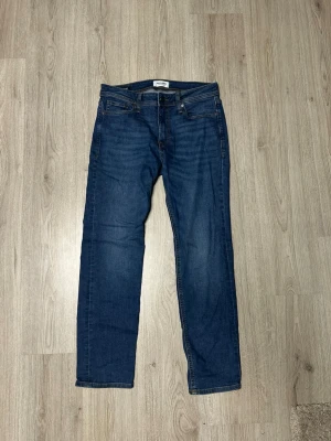 Mörkblå raka jeans  - Snygga mörkblå jeans med rak passform och klassisk femficksdesign. Jeansen har en enkel look med subtila slitningar och kontrastsömmar. Perfekta för en avslappnad stil och passar till det mesta i garderoben.