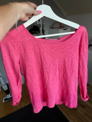 Rosa långärmad tröja med knappdetalj från 2000- talet  - Ceriserosa långärmad topp i mjukt och tunt material. Bred rund halsringning och 3/4-ärmar med uppvikbar funktion och knappdetalj. Rak, bekväm passform som passar perfekt till både vardag och sommar. 
