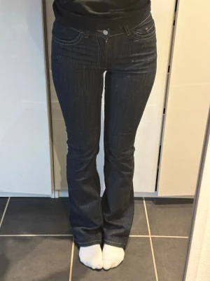 Mörkblå bootcut jeans med kontrastsömmar - Snygga mörkblå bootcut jeans med kontrastsömmar och dekorativa broderier på bakfickorna. Klassisk femficksmodell i denimtyg som sitter tajt över låren och släpper ut vid bensluten. Perfekta för en trendig och avslappnad look. Använt fåtal gånger så de är inte tvättade många gånger!