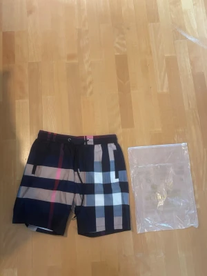 Rutiga badbyxor från Burberry - Säljer ett par blåa Burberry shorts helt nya och aldrig använda I stl L står it att de är I L men de passar I L pris går att diskutera