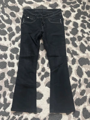 Svarta bootcut jeans med detaljer - Säljer ett par svarta bootcut jeans med vita kontrastsömmar och snygga detaljer på bakfickorna. Dom är köpta här på Plick men jag har aldrig använt dom och har inga defekter 