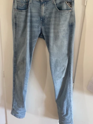 Ljusblå jeans Replay Anbass - Säljer ett par ljusblå slim jeans från Replay med klassisk femficksmodell och diskret tvättad look. Jeansen har normal midja och är tillverkade i mjuk denim. Perfekta för en avslappnad och trendig stil. 29/32