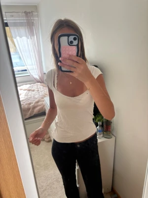 Vit ribbad topp med v-ringning - Säljer en enkel och snygg vit ribbad topp med v-ringning och korta ärmar. Toppen har en figurnära passform och är perfekt att matcha med jeans eller kjol. Superenkel att styla för en clean look.
