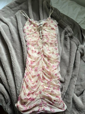 Blommig kortklänning med snörning - Supersöt kortklänning med blommigt mönster i rosa och gult. Storlek s
