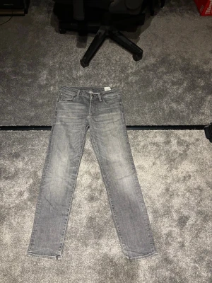 Grå raka jeans - Säljer ett par grå jeans med raka ben utan slitningar. Jeansen har klassisk femficksdesign och normal midja. Materialet är denim i bomull och färgen är ljusgrå med tvättade detaljer för en avslappnad look. W och L finns på sista bilen🍿😄✌🏾