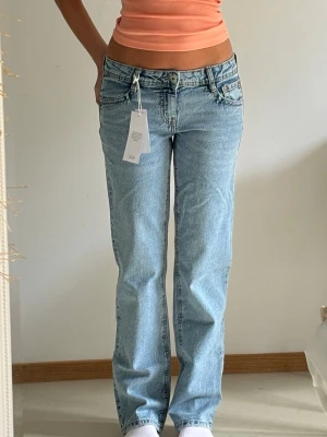 Ljusblå extra low waist straight jeans  - Säljer ett par ljusblå jeans med rak passform och extra låg midja. Jeansen har klassiska fem fickor, bälteshällor och stängs med dragkedja och knapp. Materialet är denim i bomull och de har en avslappnad, trendig look. Endast testade. 