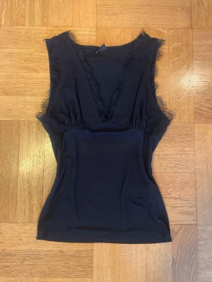 Svart spetstopp från Gina Tricot i storlek S - Snygg v-ringad topp med spets längs ringningen och som anpassar sig till kroppen. Köpt från Gina Tricot och endast använd några gånger. I storlek S men passar också XS 🖤