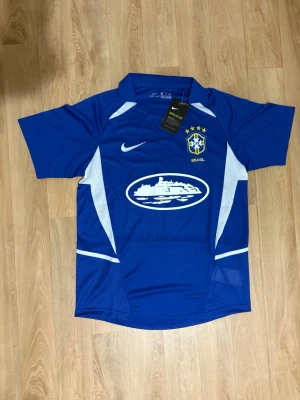 Blå Brasilien fotbollströja Nike - Snygg blå Brasilien fotbollströja från Nike med vita detaljer och Dri-FIT material. Tröjan har korta ärmar, klubbmärke och Nike-logga på bröstet samt tryckt sponsor på magen. Perfekt för träning eller match!
