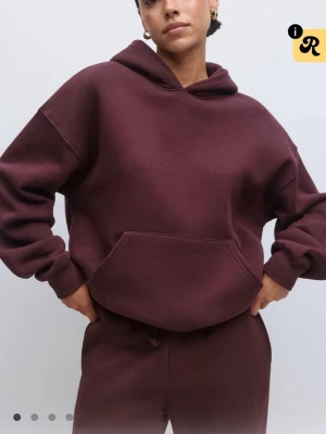 Vinröd oversized hoodie med huva - Mysig vinröd oversized hoodie med stor känguruficka och huva. Tillverkad i mjukt, tjockt material som ger en avslappnad look. Perfekt för dig som gillar en chill och enkel stil. Matcha med mjukisbyxor för en komplett outfit.