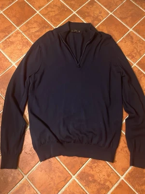 Halfzip från Mango - Snygg mörkblå Halfzip tröja från Mango i mjuk merinoull. Tröjan har en stilren half zip-dragkedja vid halsen och ribbade muddar. Perfekt för lager-på-lager under kyliga dagar. Inga defekter och pris kan diskuteras 