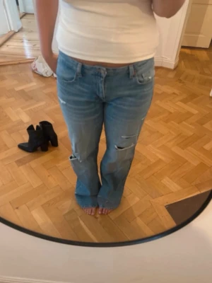 Jeans - Säljer ett par ljusblå bootcut jeans med slitningar och hål på benen. De virala jeansen från Zara, köpt på Plick, använder inte dom längre då jag tycker dom satt för löst på mig. Pris kan diskuteras