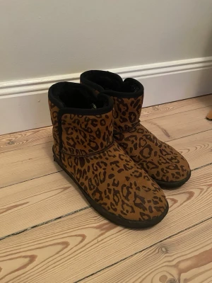 Leopardmönstrade vinterskor från DinSko - Säljer ett par bruna boots från DinSko med leopardmönster. Skorna har rund tå och är tillverkade i ett mockaliknande material. Perfekta för dig som vill sticka ut med djurmönstrade skor i höst och vinter.