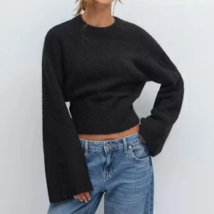 Svart stickad tröja med vida ärmar - Trendig svart stickad tröja med croppad passform och extra vida ärmar. Tröjan har rund halsringning och ribbstickade muddar vid nederkant och ärmslut. Perfekt till jeans eller kjol för en avslappnad men snygg look. Slutsåld online i nyskick!